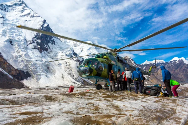 Helicopter Landing on Ice Field of Massive Glacier and People Unloading Luggage — стокове фото