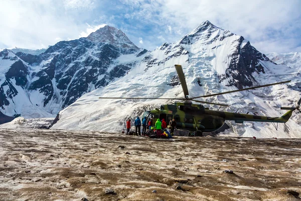Helicóptero aterrissando no campo de gelo de geleira maciça e pessoas descarregando bagagem — Fotografia de Stock