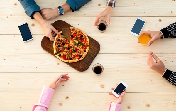 Mãos de pessoas na mesa de pizza de café de madeira com bebidas Alimentos e aparelhos eletrônicos — Fotografia de Stock