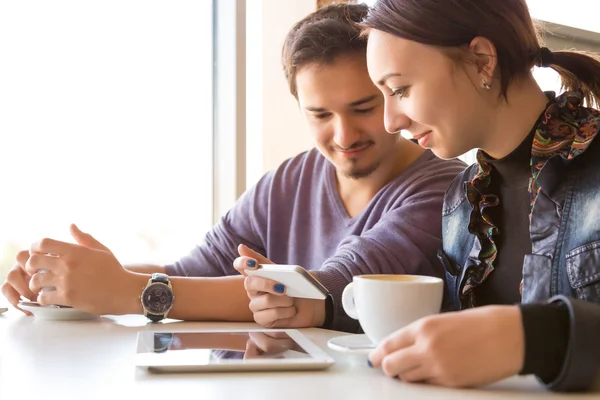 Pareja joven en la cafetería usando el teléfono — Foto de Stock