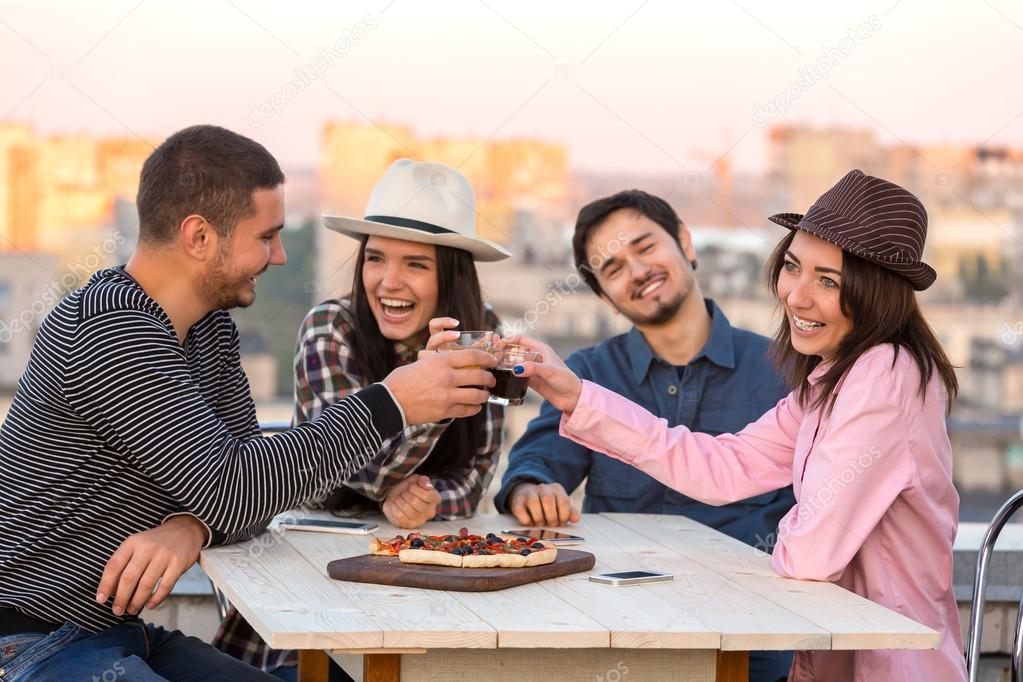 Group of Laughing People Cheers with Drinks at Pizza Cafe Table