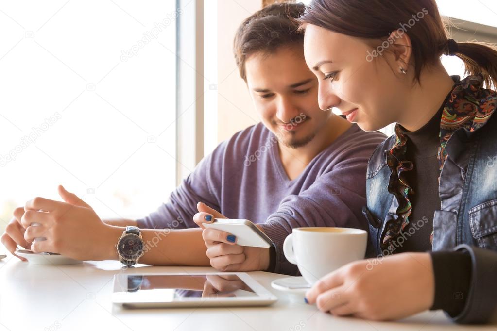 Young Couple at Coffee Shop Using Telephone