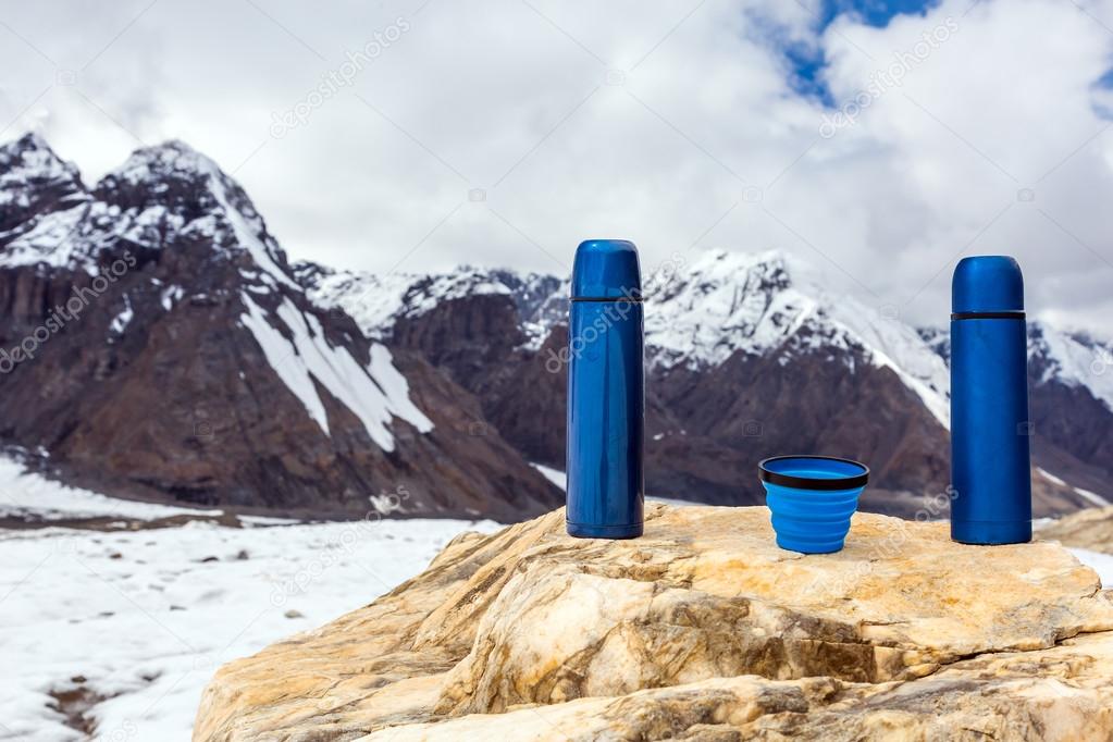 Two Blue travel thermoses Thermo Bottles and Cup on stone