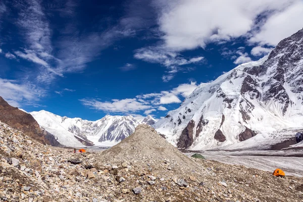 Hochgebirgspanorama mit roten und orangen Zelten auf Gletschermoräne — Stockfoto