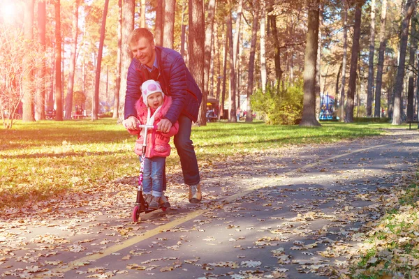 Молодой отец и счастливый ребенок верхом на мопеде в парке — стоковое фото