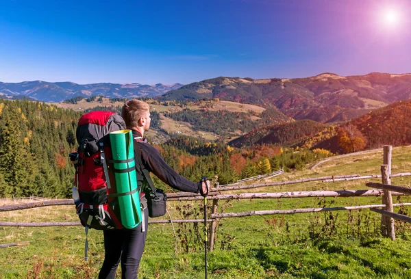 Caminhante com mochila em pé na colina apreciando vista para a montanha — Fotografia de Stock