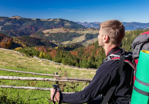 Turysta z plecaka stojący na wzgórzu, z widokiem na góry — Zdjęcie stockowe