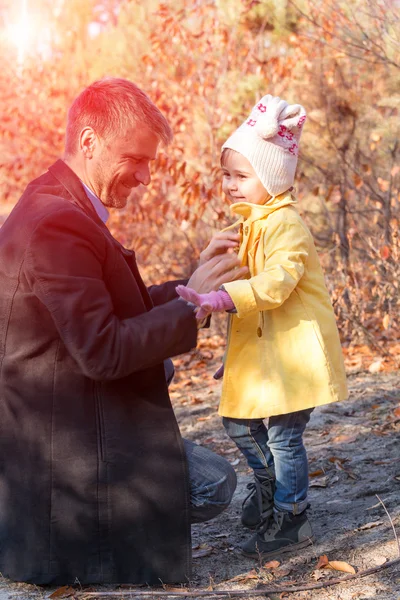 Padre ayudando a la pequeña hija a usar abrigo sol brillante —  Fotos de Stock