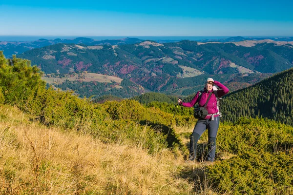 Mulher que fica no prado relvado na paisagem da montanha — Fotografia de Stock