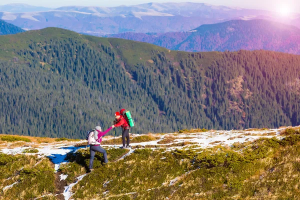 Man helping Woman to climb on steep Mountain Ridge Sun Raising — Stock Photo, Image