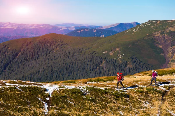 Two Hikers walking along Mountain ridge with Sun shining