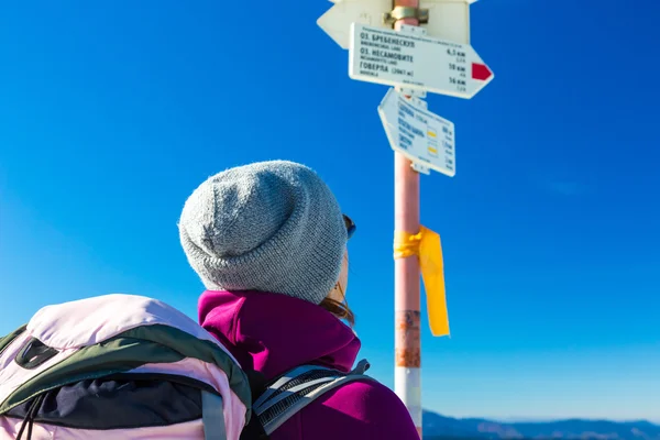 Hiker with Backpack Staying and Looking on Trail Sign — Stok fotoğraf