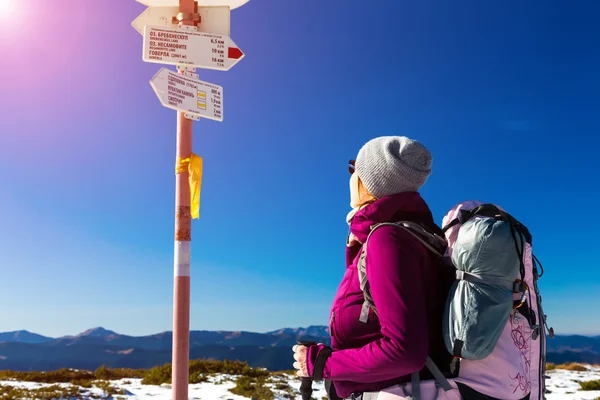 Wanderer mit Rucksack bleibt stehen und schaut auf Wegweiser — Stockfoto