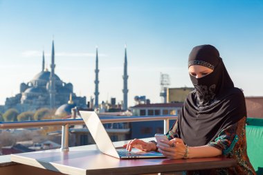 Geleneksel olarak giyinmiş Müslüman bilgisayarda çalışan kadın