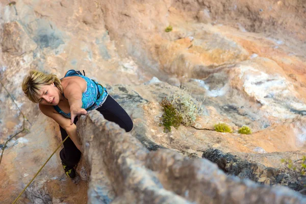 Blond mignon grimpeur sur un terrain rocheux fait mouvement difficile — Photo