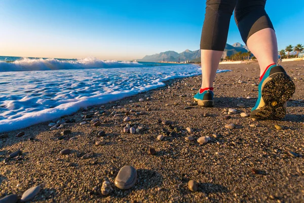 Молодая женщина, гуляющая по песчаному пляжу вдоль морского серфинга на утренней обуви Close Up — стоковое фото