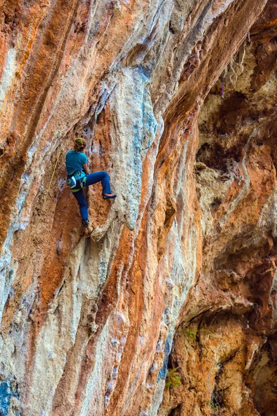 急なカラフルな岩壁リード クライミングを昇順若いロック ・ クライマー — ストック写真