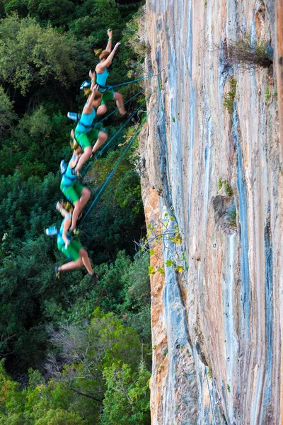 Escalada fêmea caindo do topo da parede rochosa colorida alta — Fotografia de Stock