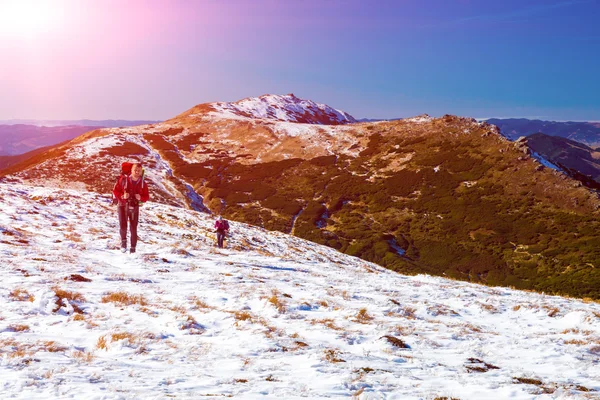 Deux randonneurs marchant sur le versant de la neige vue avec le soleil — Photo