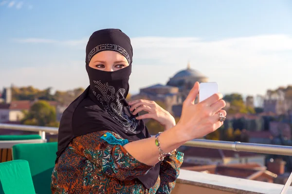 Κυρία στο μαύρο Hijab κρατώντας το τηλέφωνο — Φωτογραφία Αρχείου