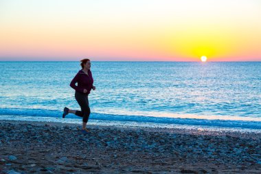 Genç kadın deniz Surf Plajı üzerinde güneş doğarken koşu