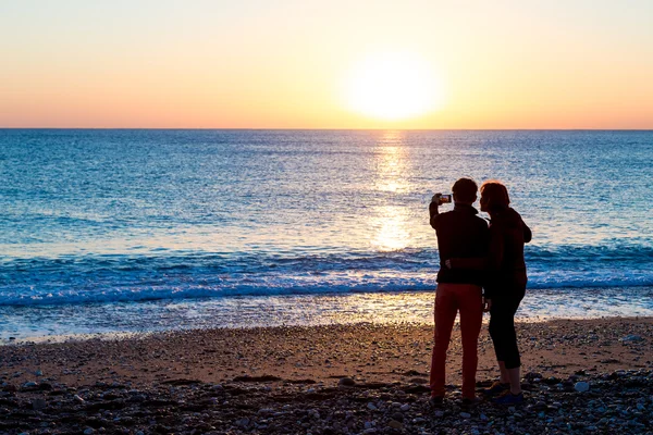 Man och kvinna vistas på stranden och ta självporträtt på telefon — Stockfoto