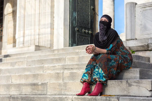 Мусульманский стиль одетый леди сидя на мраморных ступенях голубой мечети — стоковое фото