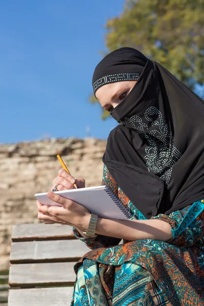 Arabic vrouw het tekenen van de schets in papier Notepad met het potlood — Stockfoto