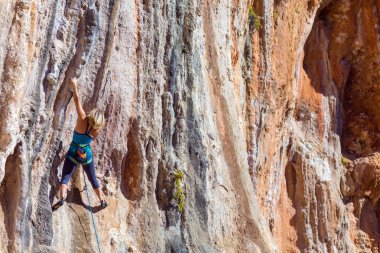 Sarışın kadın dağcı dikey turuncu kaya artan