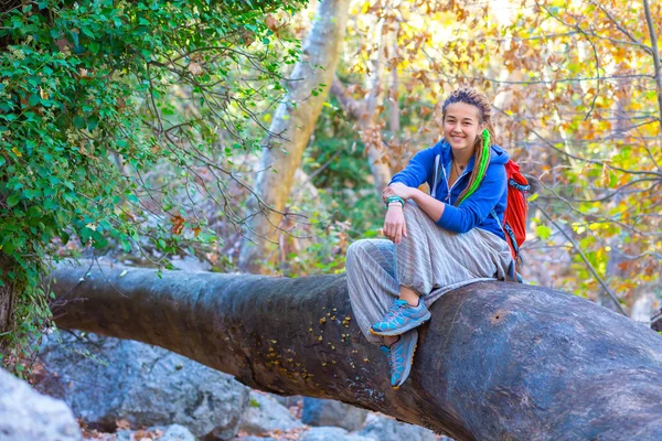 Chica alegre con mochila y ropa de estilo hippie sentado en el bosque —  Fotos de Stock