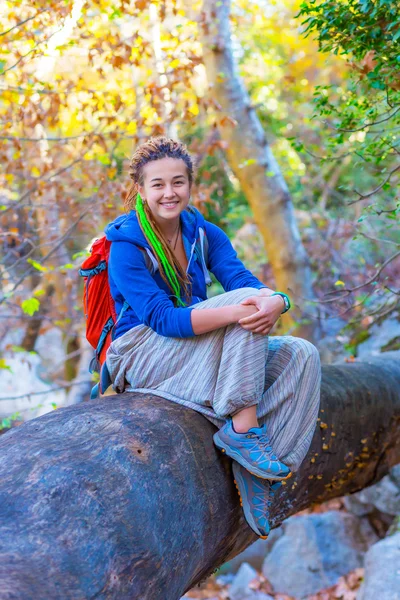 Chica alegre con mochila y ropa de estilo hippie sentado en el bosque —  Fotos de Stock