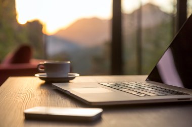 Bilgisayar kupa kahve ve siyah ahşap masa güneş doğuyor telefonla