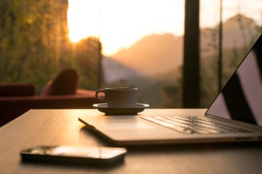 Bilgisayar kupa kahve ve siyah ahşap masa güneş doğuyor telefonla