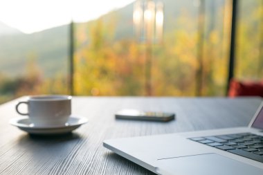 Bilgisayar kupa kahve ve siyah ahşap masa penceresinde telefon 