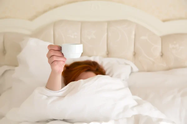 Femmina mano tenendo bianco caffè tazza Queen Size Vintage Bed — Foto Stock
