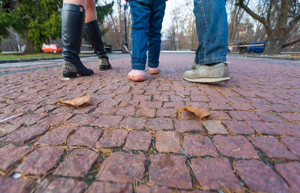 Jambes et pieds de la jeune famille Marcher sur une allée pavée du parc — Photo