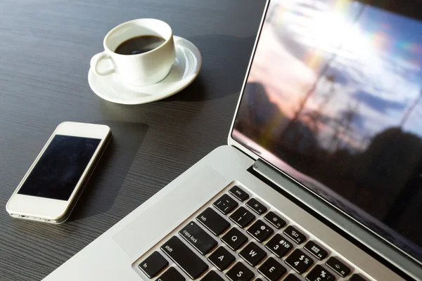 Laptop-Telefon und Kaffee auf schwarzem Holztisch — Stockfoto