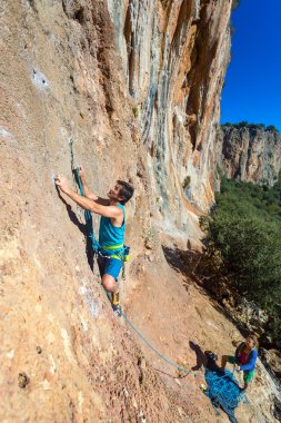 Takım dağcılar erkek ve kadın turuncu parlak kayalık duvar halat ve dişli ile artan