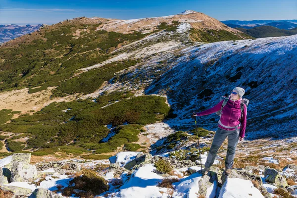 Θηλυκό πεζοπόρος που στέκεται στα χιονισμένα βράχια θαυμάζοντας γραφική θέα προς το βουνό του χειμώνα — Φωτογραφία Αρχείου