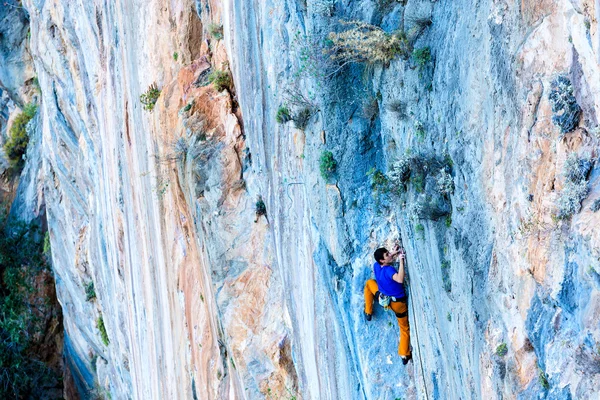 Ярко светящийся оранжево-голубой камень и альпинист — стоковое фото