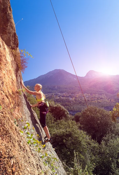 Гарненька блондинка дівчинка сходження помаранчеві скелі гори світить сонце — стокове фото