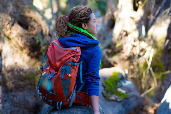 Ormanda oturan sırt çantası ve hippi tarzı giyim ile neşeli kız — Stok fotoğraf