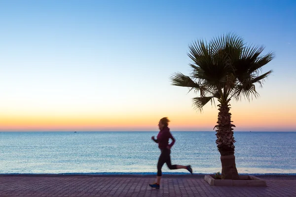 Junge Frau joggt an der Strandpromenade und macht Morgenfitness — Stockfoto