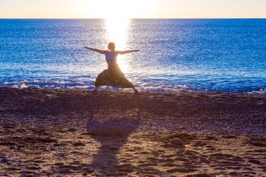 Genç kadının yoga egzersiz tropik sahilde güneş doğarken yapması