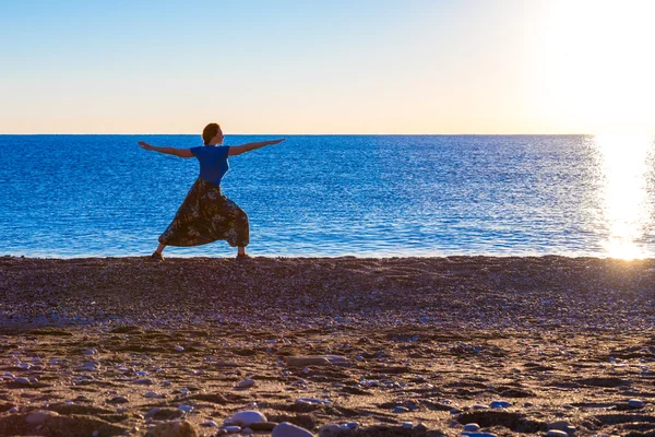 Fiatal nő jóga gyakorlása a tropical Beach napkeltekor — Stock Fotó