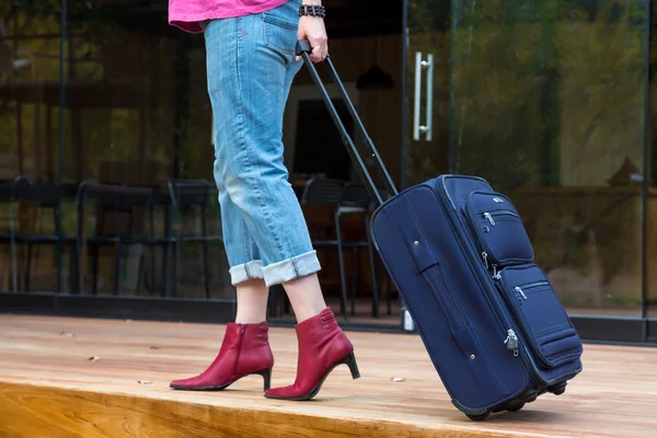 Persona che cammina sulla terrazza in legno tirando valigia da viaggio — Foto Stock