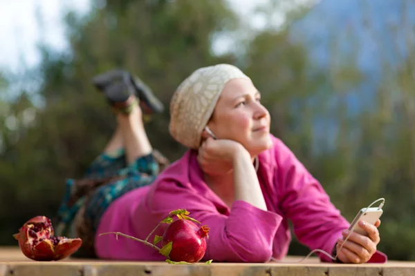 Mujer sonriente escuchando música en auriculares por teléfono — Foto de Stock