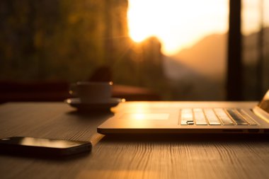 Computer Coffee Mug and Telephone on black wood table sun rising clipart