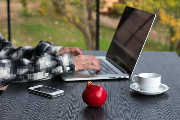 Persoon die werkt op Computer met telefoon koffiemok op zwarte houten tafel — Stockfoto
