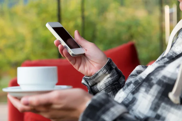 Persona con taza de café y teléfono en el vestíbulo del hotel — Foto de Stock